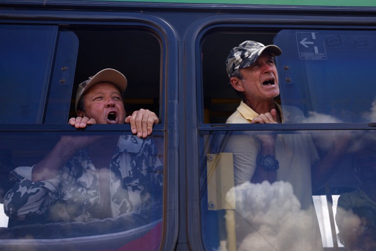 Bolsonaro supporters react from the window of a bus as they are detained