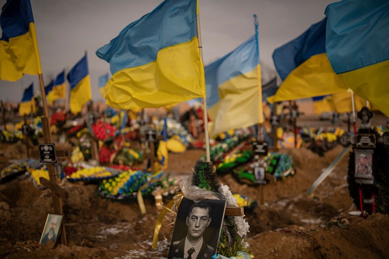 A photograph of a Ukrainian serviceman is placed on his grave in the Alley of Glory part of the cemetery in Kharkiv, Ukraine, Friday, Feb. 24, 2023. Ukraine's leader pledged Friday to push for victory in 2023 as he and other Ukrainians marked the somber anniversary of the Russian invasion that upended their lives and Europe's security. (AP Photo/Vadim Ghirda)