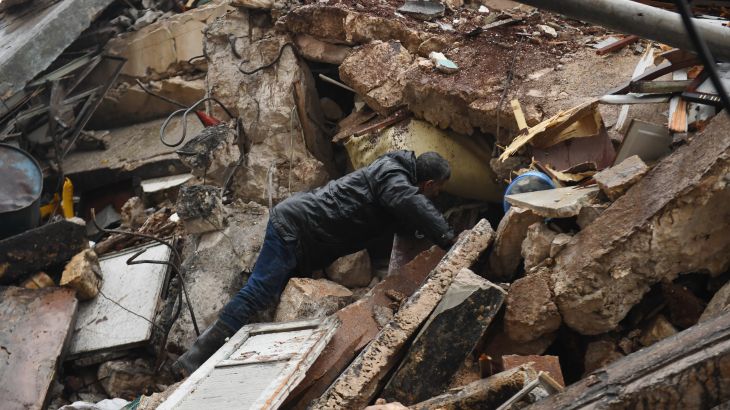A man looks for survivors under the rubble of a collapsed building after an earthquake in the regime-controlled northern Syrian city of Aleppo on February 6, 2023. A 7.8-magnitude earthquake hit Turkey and Syria early on February 6, killing hundreds of people as they slept, levelling buildings and sending tremors that were felt as far away as the island of Cyprus, Egypt and Iraq.