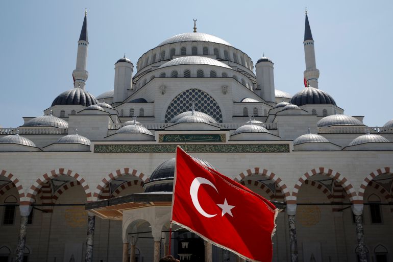 A man waves a Turkish flag at the courtyard of the Grand Camlica Mosque in Istanbul, Turkey
