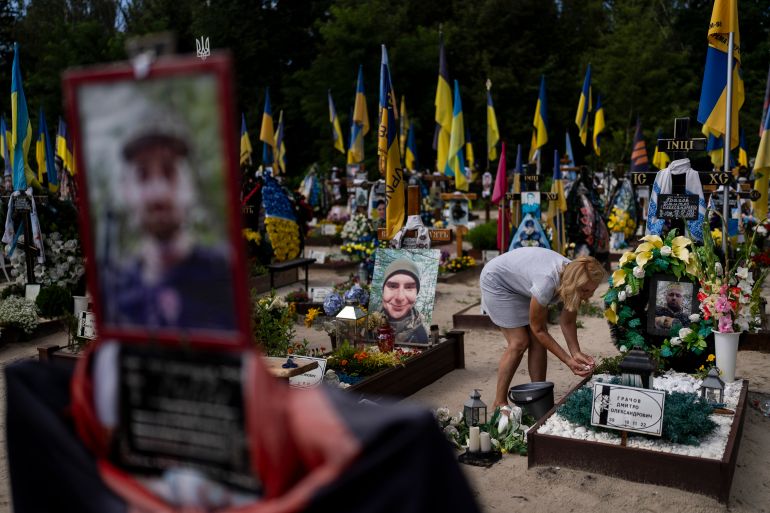A woman tends to the grave of her son, a Ukrainian soldier who was killed in the war against Russia, in Kyiv, Ukraine.