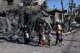 people stand in front of destroyed building