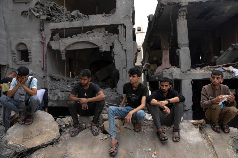 Palestinians sist outside a building destroyed in Israeli bombardment in Rafah refugee camp in Gaza Strip on Tuesday, Oct. 17, 2023. (AP Photo/Fatima Shbair)