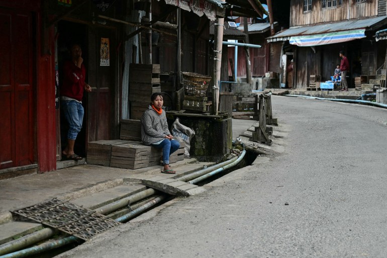 A handful of residents outside their houses on a deserted street in Namhsan. It appears very quiet.