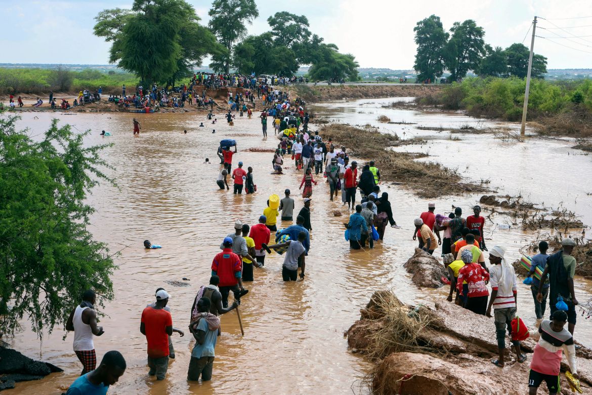 People wade over flood waters after a section of road was destroyed by floods at Mororo, border of Tana River and Garissa, North Eastern Kenya.