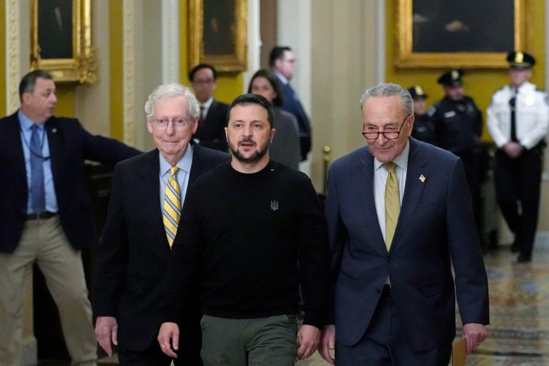 Ukrainian President Volodymyr Zelenskyy walks through the Capitol. Mitch McConnell is on one side and Chuck Schumer on the other.