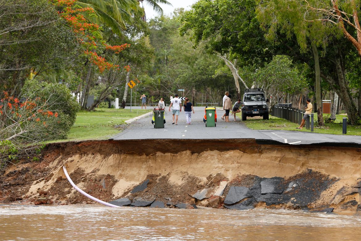Stranded residents stand on a road, a large section of which has washed away, in the suburb of Holloways Beach in Cairns, Australia.