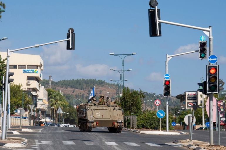 An Israeli armoured vehicle drives down the street of an Israeli community