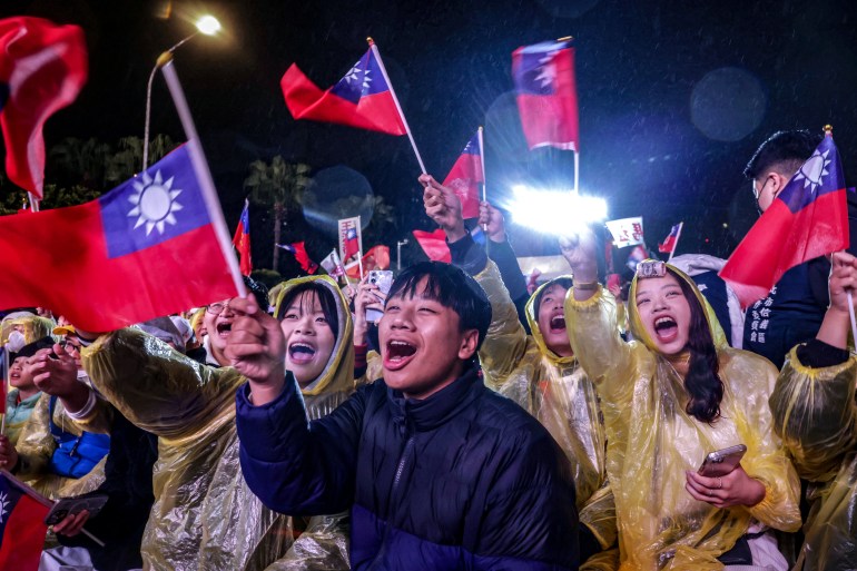 Supporters of the KMT at a campaign rally. They are holding Taiwan flags and shouting. They look enthusiastic