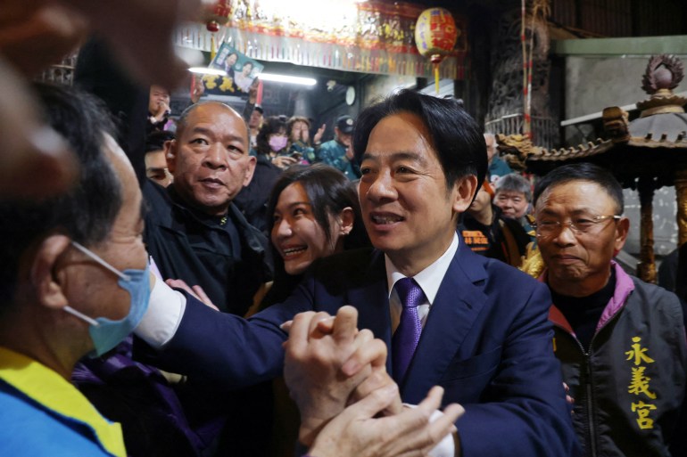Taiwan presidential candidate William Lai greeting supporters. He is smiling and grasping people's outstretched hands