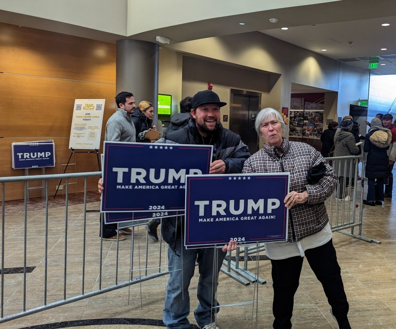 Two people holding "Trump" signs