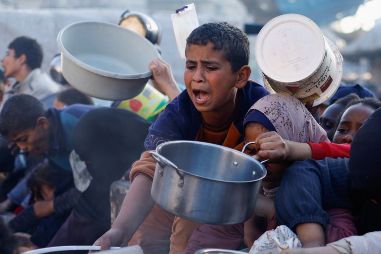 A child reacts, as Palestinians wait to receive food during the Muslim holy fasting month of Ramadan, as the conflict between Israel and Hamas continues, in Rafah