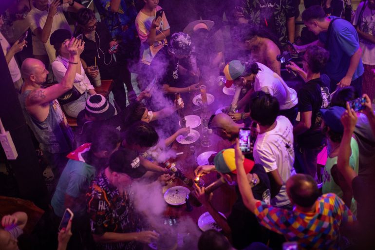 People smoke out of bongs during a speed contest to finish 3 grams, at the Green Party in Bangkok, Thailand