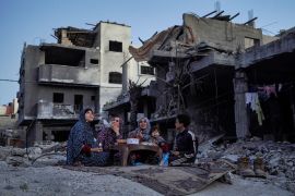 The Palestinian Al-Naji family eats an iftar meal, the breaking of fast, amidst the ruins of their family house, on the first day of the Muslim holy fasting month of Ramadan, in Deir el-Balah in the central Gaza Strip. [AFP]