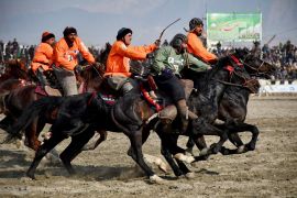 Riders of the Yama Petroleum (orange) and Baghlan teams competing at the Buzkashi league tournament final in Mazar-i-Sharif. [Atif Aryan/AFP]