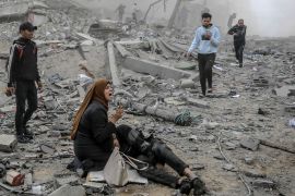 a woman cries out as she sits in the dust of a destroyed building