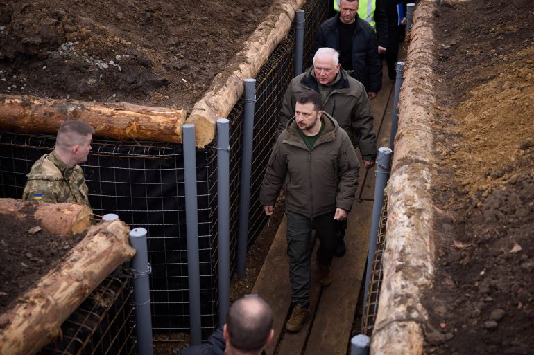 Ukrainian President Volodymyr Zelenskyy walking through a newly-built trench