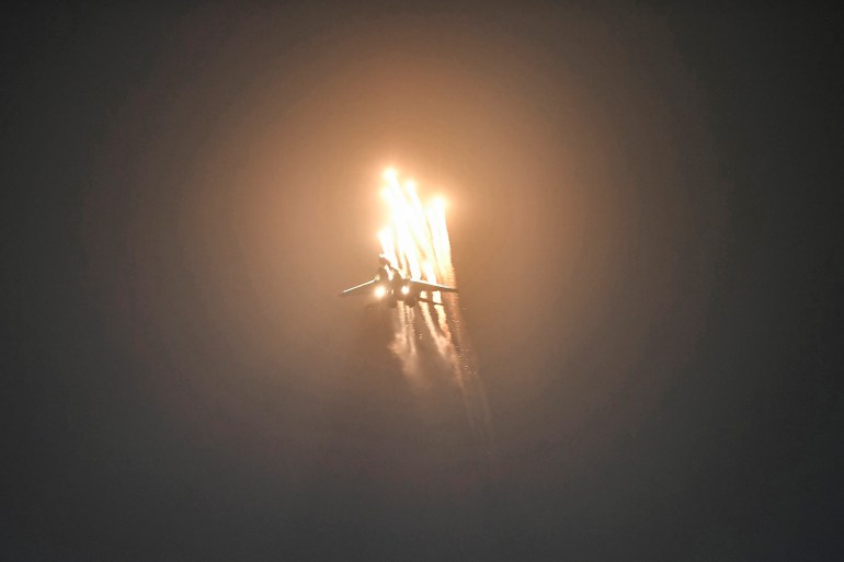A Sukhoi Su-30 fighter takes part in an aerial display it is releasing flares with the flames lighting up the night sky.