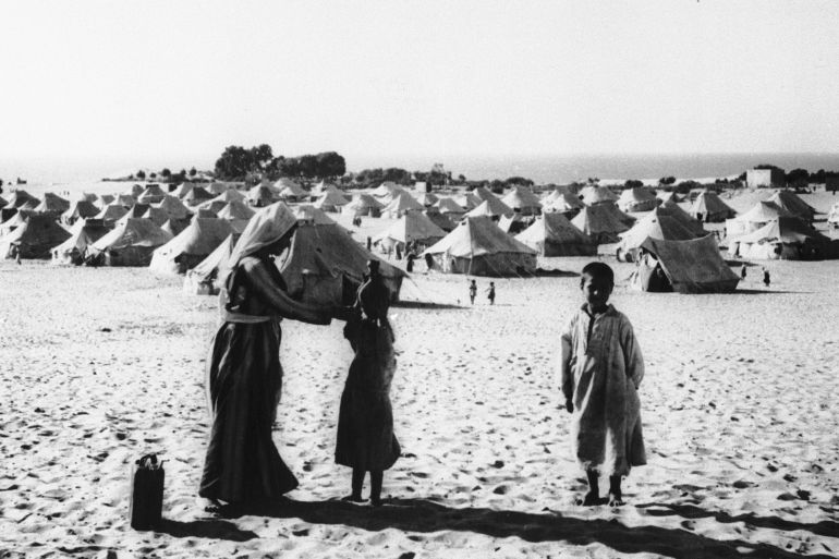 A mother and her children are seen at tent city in the Gaza area of Egyptian-occupied Palestine where about 216,000 Arab refugees live in worn-out tents, July 23, 1949. The woman is teaching her daughter how to carry a water jug on her head. (AP Photo/S. Swinton)