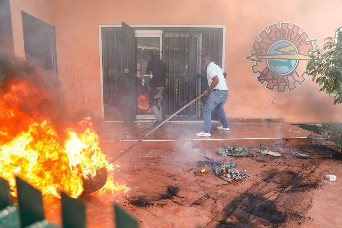 Workers put down a fire set at an office of Haiti's power company during a protest to demand the resignation of Prime Minister Ariel Henry