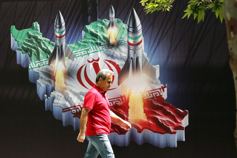 An Iranian man walks past a huge anti-Israeli banner