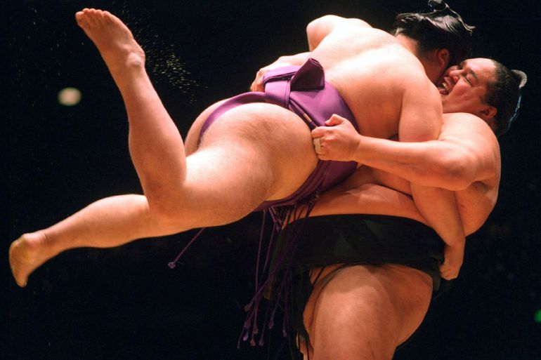 Sumo wrestler Akebono (R) has his opponent Kotonowaka airborne during a tournament.