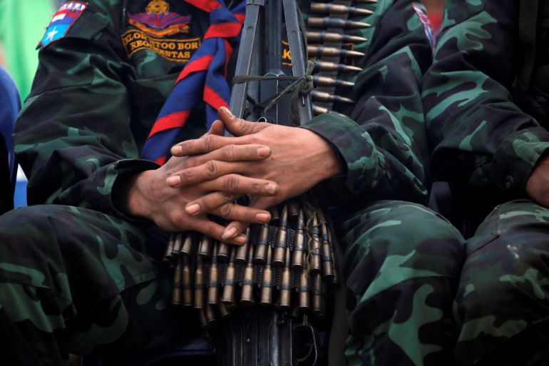 A close up of a KNU soldier with bullets around his neck and on his lap.
