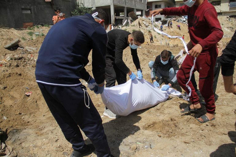 Palestinians cover a body, which was buried in a mass grave