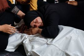 A woman grieves next to the bodies of family members killed in Israeli strikes in Rafah [Mohammed Salem/Reuters]