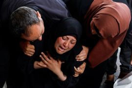 A woman grieves next to the bodies of family members killed in Israeli strikes in Rafah, in the southern Gaza Strip, on April 16, 2024 [Mohammed Salem/Reuters]
