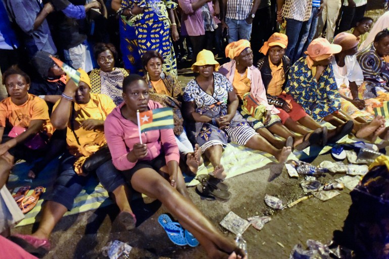 Togolese opposition supporters sit on a street as they keep an all-night vigil to press for constitutional reform in 2017