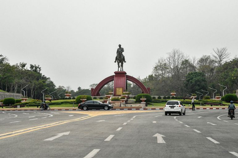 A view of a wide road in Naypyidaw. There is a monument to General Aung San at the end. A couple of cars are on the road.