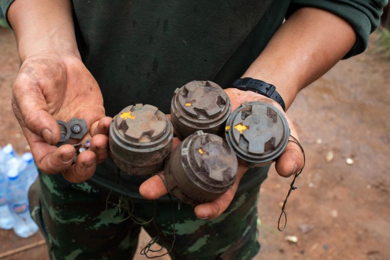A fighter from the anti-coup Karenni Nationalities Defence Force holding a selection of landmines in his hands.