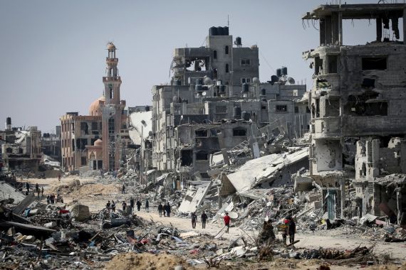 People walk amid the rubble of buildings destroyed during Israeli bombardment in Khan Yunis