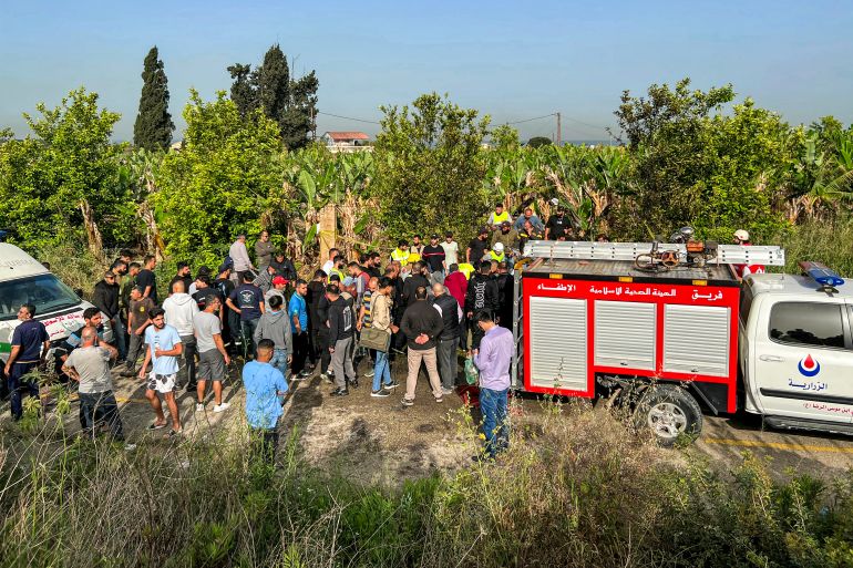 People gather at the site of an Israeli strike on a vehicle in the Adloun plain area, between Lebanon's southern cities of Sidon and Tyre