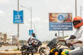Motorcyclists drive past campaign posters of Union pour la Republique (UNIR) governing party, in Lome on April 24, 2024 [File: Dodo Adogli/AFP]