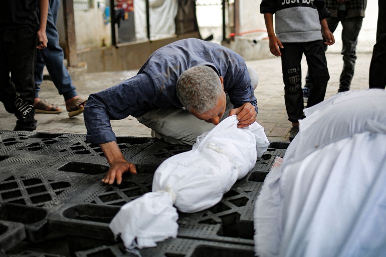 A man kisses the shrouded corpse of a child killed in overnight Israeli bombardment