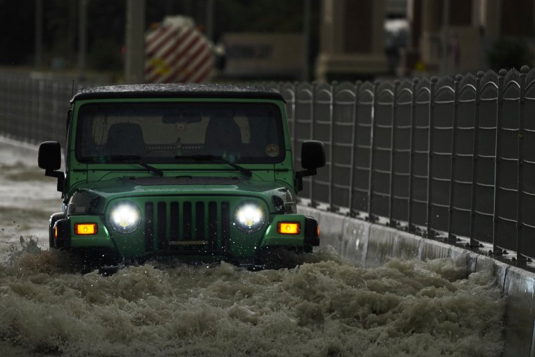 An SUV passes through standing water in Dubai, United Arab Emirates, Tuesday, April 16, 2024.