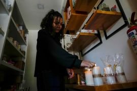 A woman in Quito, Ecuador, lights candles in her store on April 16 in preparation for power outages [Dolores Ochoa/AP]