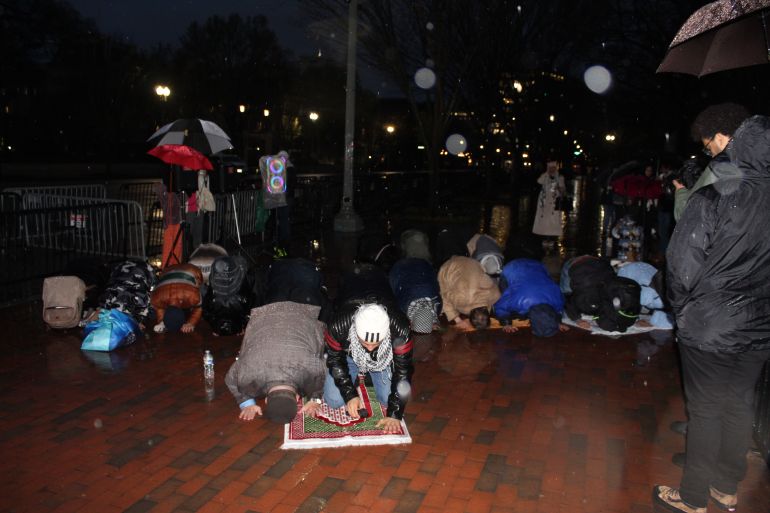 People bow down in prayer at side walk