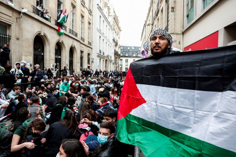 A person holds a Palestinian flag as people take part in the occupation of a street in front of the building of the Sciences Po University in support of Palestinians in Gaza, during the ongoing conflict between Israel and the Palestinian Islamist group Hamas, in Paris, France, April 26, 2024. REUTERS/Gonzalo Fuentes
