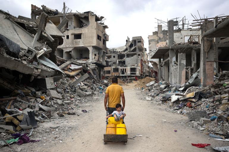 A Palestinian man pulls a cart on a road lined with destroyed buildings in Khan Yunis