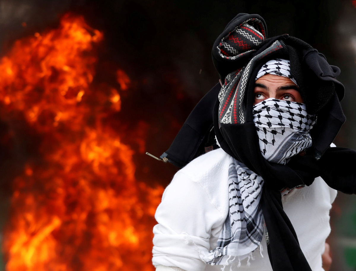 A Palestinian protester throws a stone at Israeli forces during a protest against US President Donald Trump's decision to recognise Jerusalem as the capital of Israel, by the Qalandia checkpoint, near the occupied West Bank city of Ramallah. [Goran Tomasevic/Reuters]
