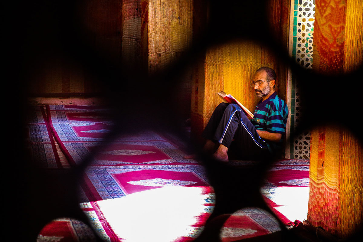 A man sits in the madrasa, reading the Quran. It is encouraged during the holy month to use your time to read and practise recitations of the Quran, which was revealed to the Prophet Muhammad during the month of Ramadan 1,408 years ago. [Venetia Menzies/Al Jazeera]
