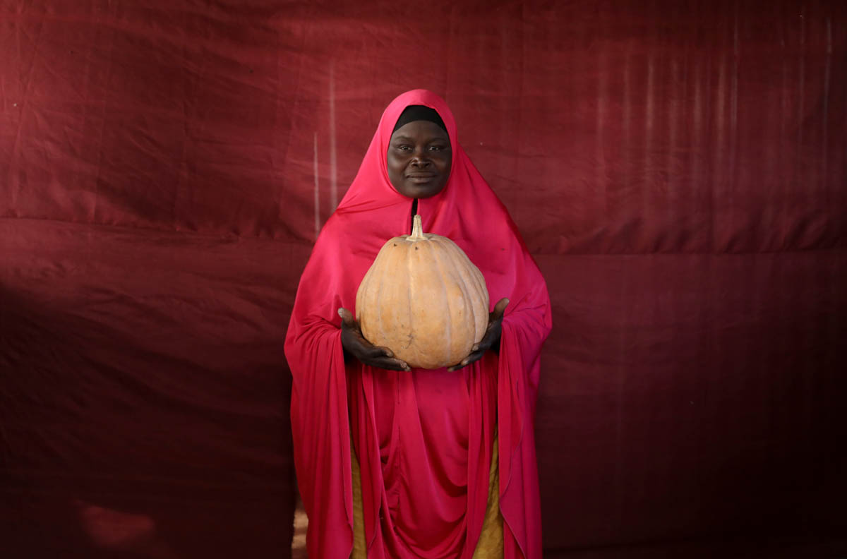Aisha Umaru Gaye holds up a pumpkin. [Afolabi Sotunde/Reuters]