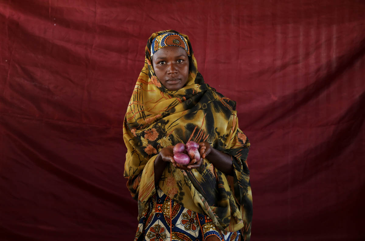 Aisha Alhajji Audu holds four small red onions in her hand. [Afolabi Sotunde/Reuters]
