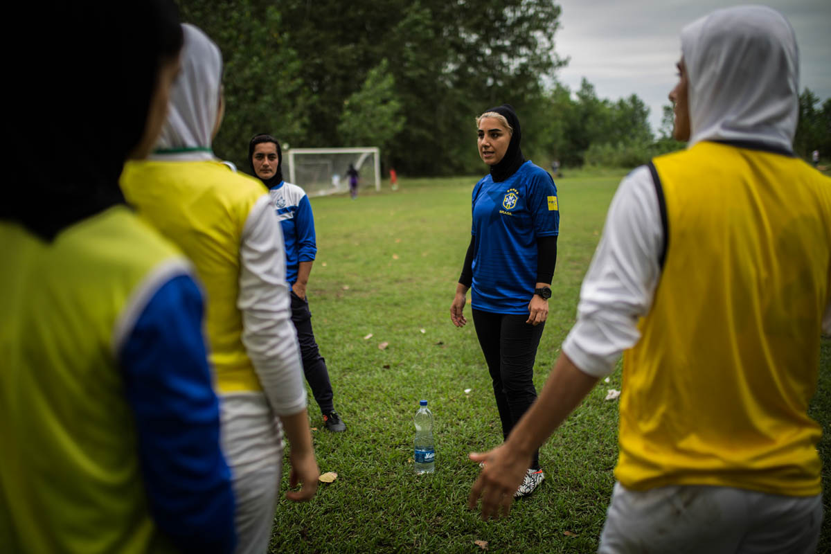 Maryam Irandoost, the women's team head coach in the blue jersey, has spent her professional life as a football player in Iran, and now heads the newly revived team. [Mohammad Ali Najib/Al Jazeera]