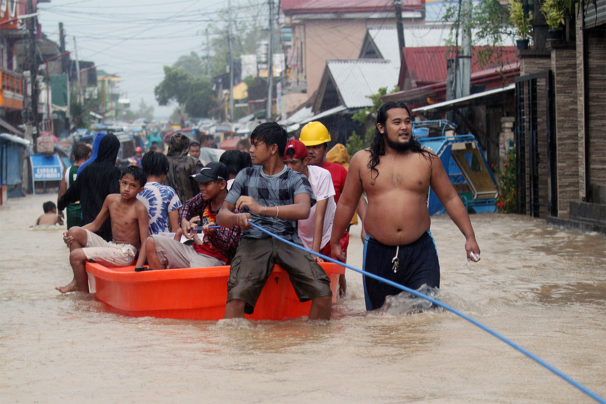 December - Filipino residents ride on a boat during a rescue operation at in the town of Bulan, Sorsogon province. Three people were killed in a landslide in the City of Legazpi, Albay province, and hundreds of families were evacuated to higher grounds in Sorsogon province after a tropical depression brought heavy rains. [Romedor Gloriane/EPA]