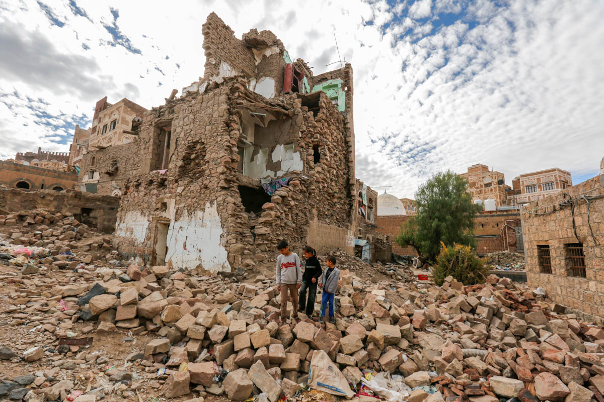 Siblings Mohammed, Batool and Luai Ali Zaid walk on the rubble of their neighbour's house, which was destroyed by conflict in the Old City of Sanaa. The children fled the area with their family after the incident but have since returned. [Mohammed Hamoud/UNHCR/Al Jazeera]