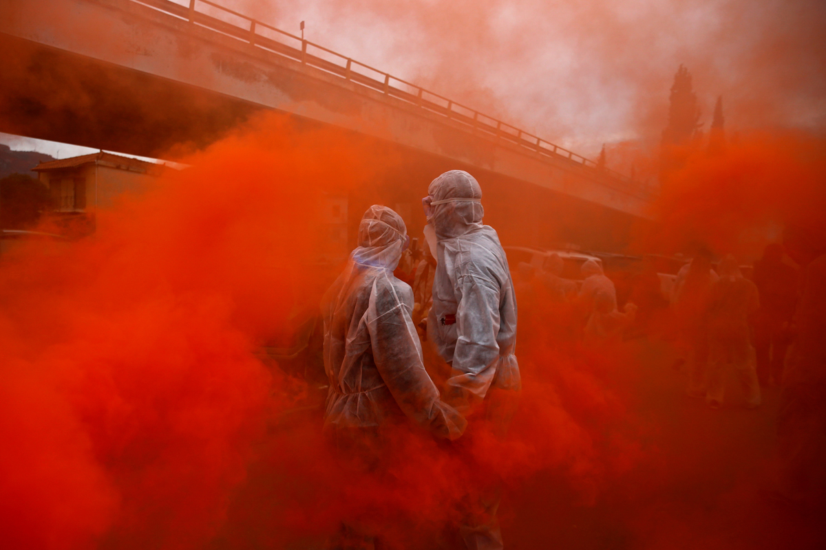 Tworevellers stand amid flare smoke In the port town of Galaxidi, Greece. They are celebrating Ash Monday with a colourful 'flour war', a traditional festivity marking the end of carnival season and the start of the 40-day Lent period until Orthodox Easter. [Alkis Konstantinidis/Reuters]